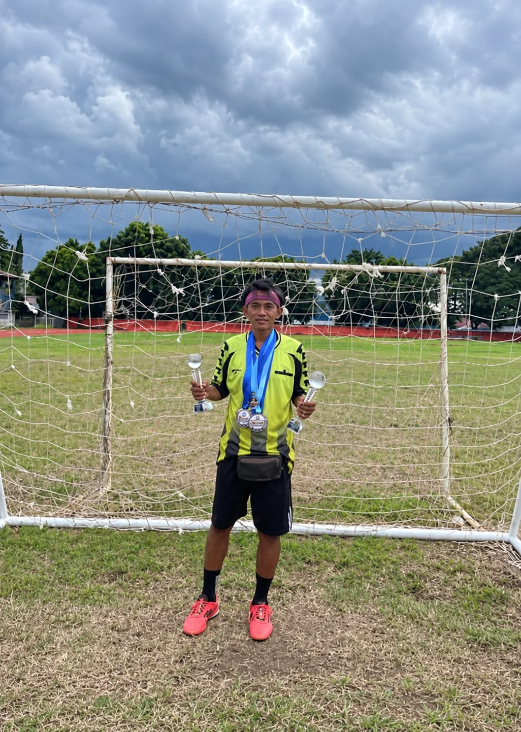 Entrenador de Bethel FC sosteniendo trofeos de las victorias en las divisiones U-15 y U-18