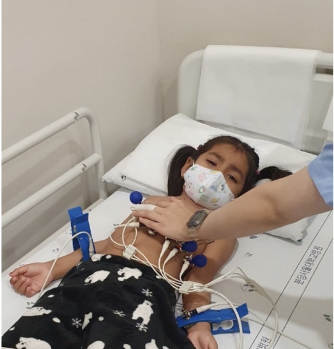 Sophia in a hospital bed wearing a mask before her heart surgery
