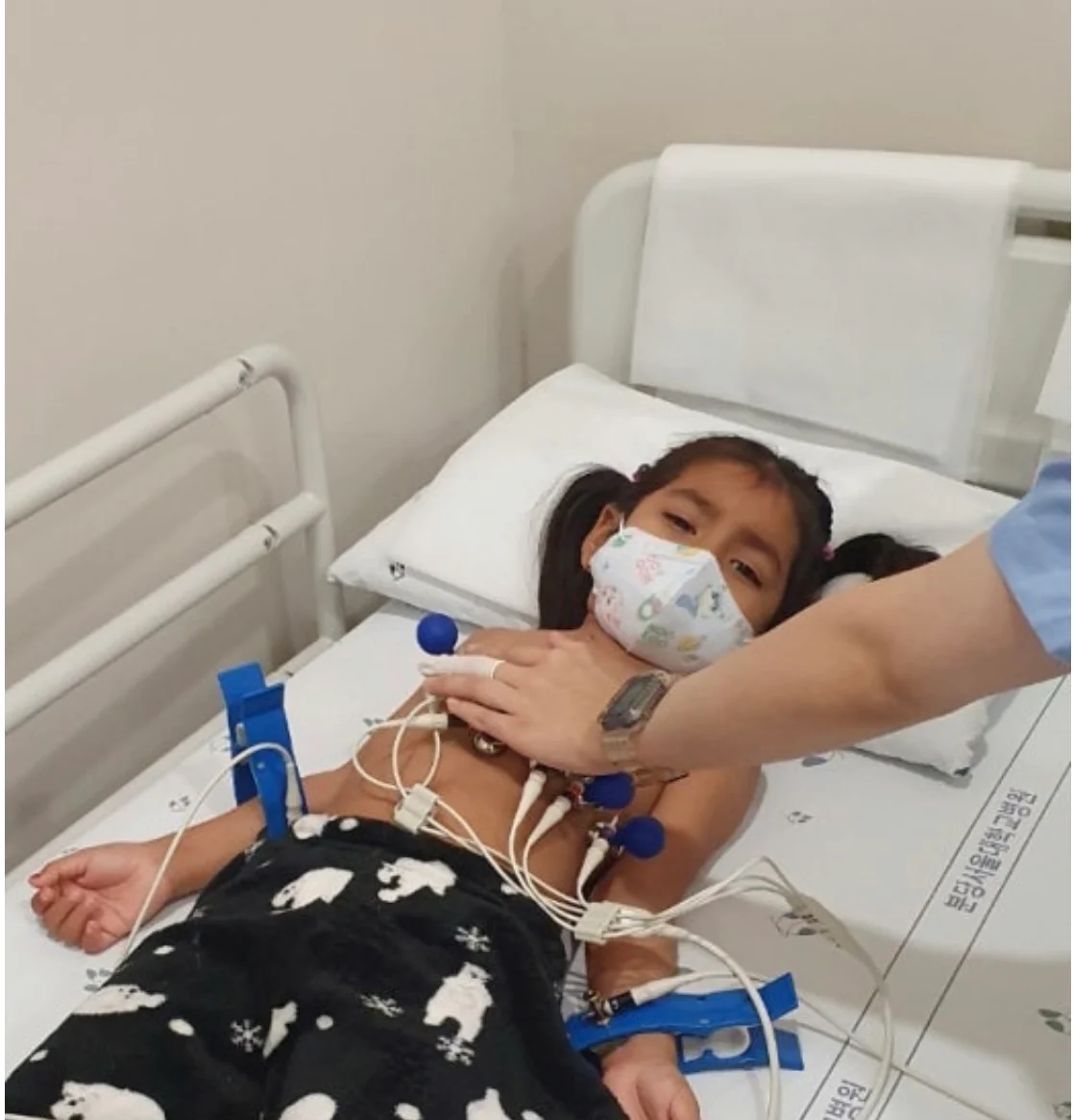 Sophia in a hospital bed wearing a mask before her heart surgery